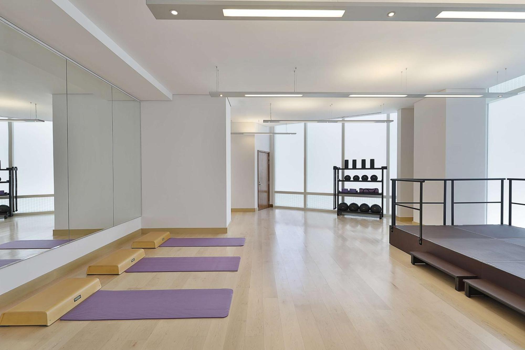 Hilton Riyadh Hotel & Residences Exteriör bild The photo depicts a spacious exercise or workout studio. It features wooden flooring and a large mirror on one wall. There are three purple yoga mats neatly placed on the floor, and a small set of wooden steps beside them. In the background, there is