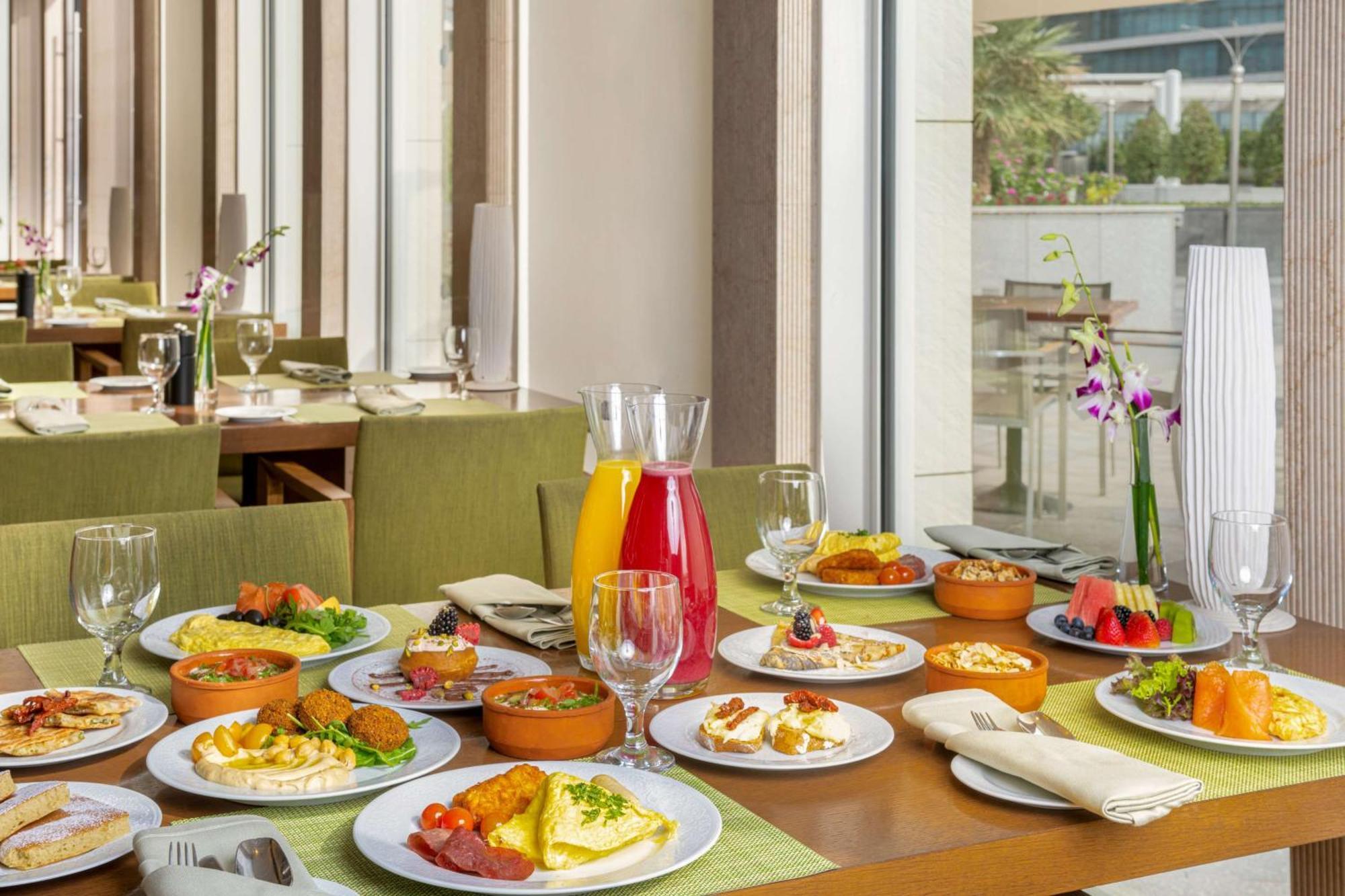 Hilton Riyadh Hotel & Residences Exteriör bild The photo showcases a beautifully arranged dining table filled with a variety of dishes. There are multiple plates featuring an assortment of foods, including salads, appetizers, and main courses, presented in a vibrant and appetizing manner. Additio